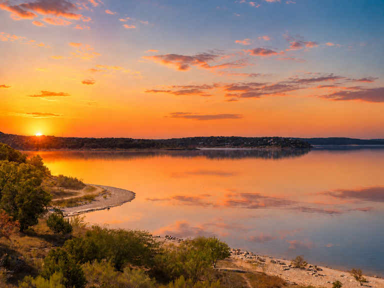 Sunrise over Canyon Lake, Texas, with exposed rocky shoreline and a low water line along a calm cove, hillside homes in the distance