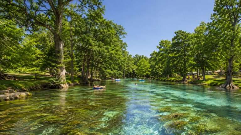 Tubers floating the clear, spring-fed San Marcos River past cypress-lined banks in the Texas Hill Country