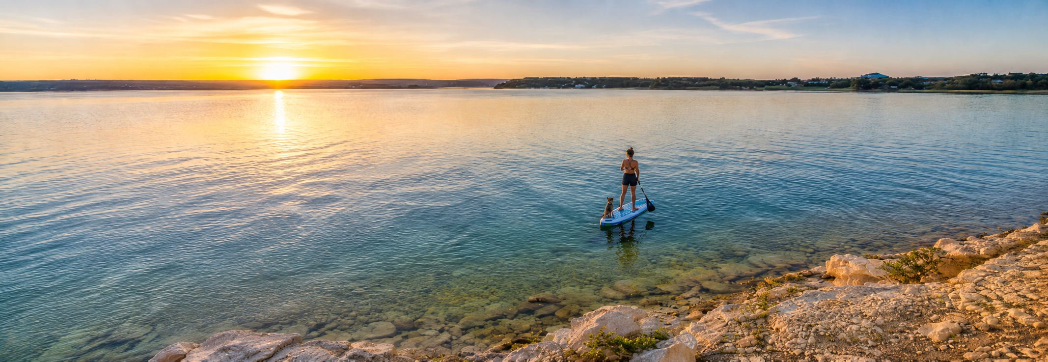Paddleboarder at sunset on Canyon Lake, Texas — the Hill Country reservoir buyers picture when moving to Canyon Lake