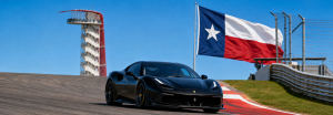 Circuit of the Americas race track with a black Ferrari, the COTA observation tower, and the Texas flag