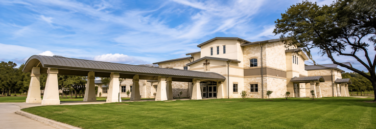 Private schools Cedar Park TX campus with Texas limestone, a covered walkway, and a cross over the entrance