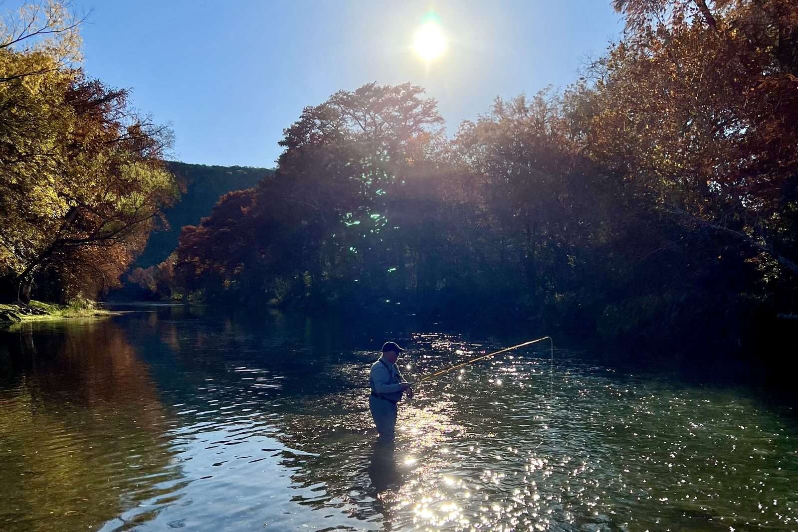 Angler wading the Guadalupe River in late-afternoon light