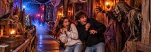 Haunted houses in Central Texas: two teens recoil from a costumed monster in a foggy, lantern-lit haunted house walkway
